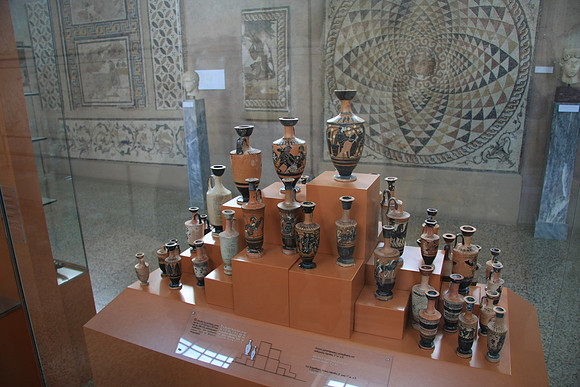 Pottery with mosaic floor in the background recovered from the ruins.