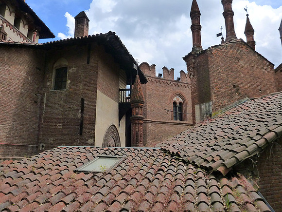 Terracotta roofs, crenelations, and spires. It is a replica of the Fénis Castle in Valle d'Aosta.